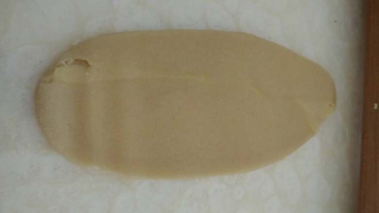 蛋黄酥,把包裹住油酥的面团用擀面杖擀成牛舌状，不需要太长，均匀点就好，然后从上往下卷起来，用湿毛巾盖好松弛十分钟