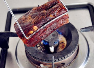 迷倒众生的烟熏味儿：腊肉夹馍 ,若腊肉皮上有猪毛，就用夹子夹住放小火上烧烤，等表皮烧黑后关火。
   若猪皮上很干净，没猪毛，这步可以省略，直接煮。
