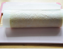 烫面蛋糕卷,提起靠近自己的一侧油纸，借助擀面杖将蛋糕卷卷起（具体卷法可以百度搜视频），放入冰箱冷藏至少30分钟定型，然后取出切块即可。