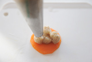 【梅花丸子汤】,取一片胡萝卜，在上面挤上六个小球形成梅花形，需要用剪刀辅助剪断连续不断的虾泥；