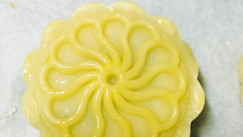 广式豆沙蛋黄月饼,轻轻在月饼表面刷一层蛋黄液，不要刷太多，以免烤出的花纹不清晰