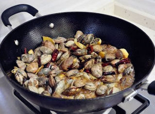 麻辣蛤蜊,继续大火，继续翻炒，过一会就会看到锅里会多出一些水份，这就是先不要放盐的原因。
     蛤蜊在打开壳之前会先出水，而且是鲜咸的。
