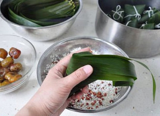 四角粽子的包法：红豆蜜枣粽子,再将多出的苇叶沿粽形折起，全部缠绕在粽子上。