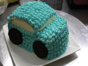 小男孩最爱的小汽车蛋糕 ,把剩下的淡奶油掺少许蓝色食用色素，用裱花袋在汽车表面挤上花，留出窗户