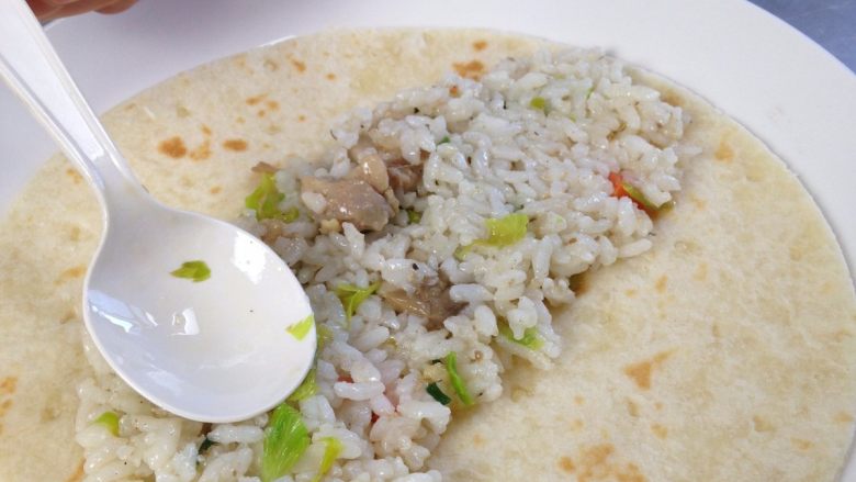 Enchiladas,炒好的米饭用勺子铺在加热好的饼皮中间