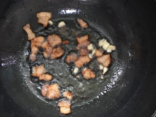 爆炒双色甘蓝,将三层肉放入锅内放少许的油煸香，放入蒜瓣炒香。