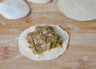 羊肉芦笋香菇饺子,挖一勺羊肉馅放在饺子皮上。