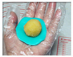 冰皮奶黄月饼,取一个饼皮面团放手心压扁，中间放入奶黄球；