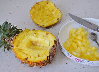 菠萝季独有的椰浆菠萝糯米饭 ,菠萝对半切开，用小刀先沿内边划一圈，然后再给菠萝肉划井形，最后用小勺将菠萝肉挖出。