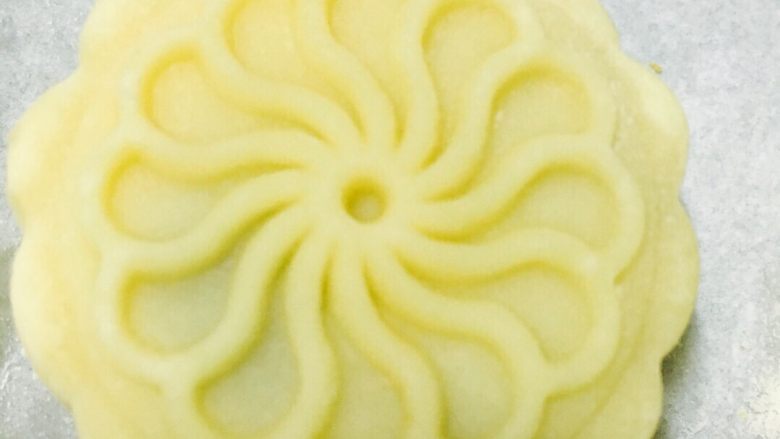 广式红豆沙蛋黄月饼,将包好的月饼胚子放到烤盘上，用月饼模轻轻向下按压，挤出月饼。