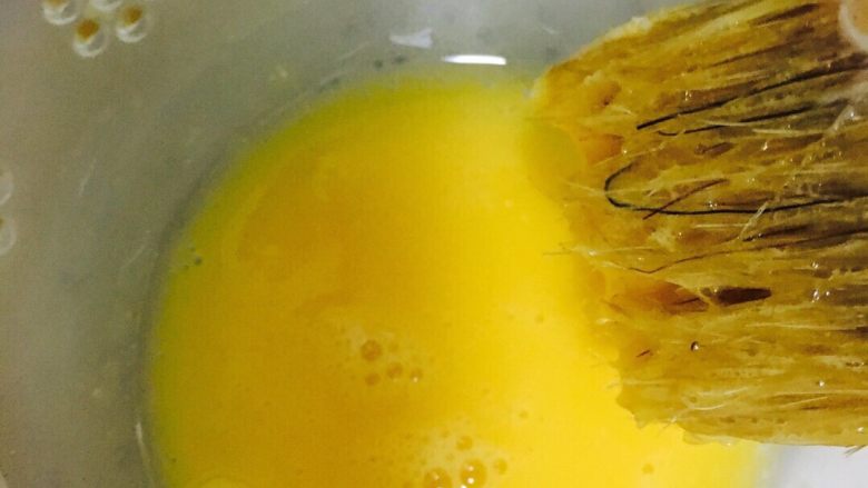 广式红豆沙蛋黄月饼,用毛刷蘸蛋液，在碗边刮去多余蛋液，不能有太多。