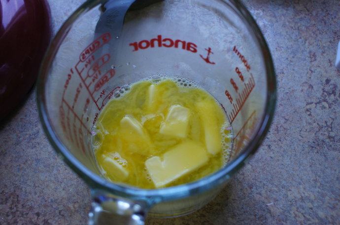 高筋面粉也可以做出柔软海绵蛋糕 ,在一个容器里加入黄油，倒入热开水，搅拌均匀。