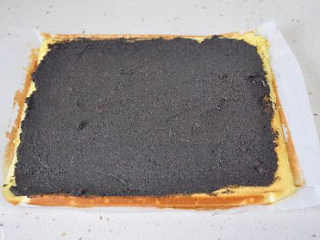 【红枣黑芝麻蛋糕卷】,取出不要揭掉烘焙纸的放置，自然降温后均匀抹平一层黑芝麻馅。