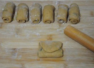 红火喜庆的大枣虾仁堡,将小面卷按扁擀成长形薄片，再将面片对折成三片的正方形面包坯。