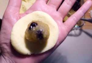 宝岛名吃——蓝莓凤梨酥 ,取一份酥皮在手掌中按扁，中间薄四周厚些，将馅料（蓝莓干每颗包入4-5粒即可）包进去