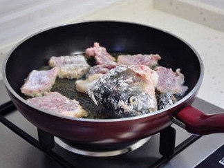 最美川式下饭菜：酸菜鱼 ,炒锅中油热后，放入鱼头鱼骨，小火慢煎。