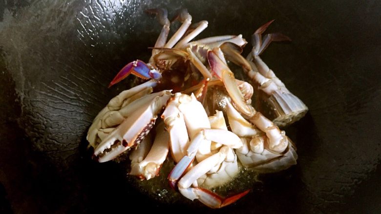 梭子蟹炒年糕,锅烧热，放油（比平时炒菜多一点），油七分热，将螃蟹的切面放油锅中烧炸，定型。