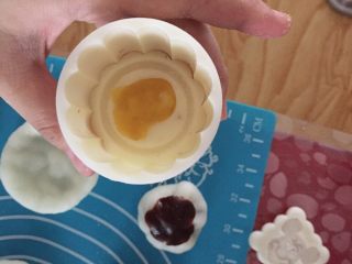 手工制作:冰皮月饼,在模型上撒上一层月饼皮粉防止粘连，把刚才捏好的冰皮放进模型里，先轻轻压，然后在用力压一下