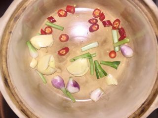 酒蒸蛤蜊,将瓦锅烧至出白烟，再放入葱头、葱白，辣椒和蒜头，炒至出香味。