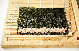 创意无限的花样寿司【小花寿司】,取一片海苔，一端铺上少量的鱼籽米饭；