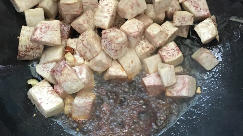 #年夜饭#猪蹄芋头煲,将炸好的芋头放入锅中，翻炒几下，放入两小勺酱油翻炒。