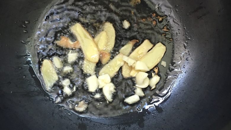 #红烧栗子鸡#,锅中倒入少许油，加热，放姜片蒜瓣爆香。