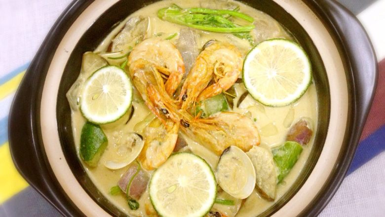 泰式海鲜绿咖喱,倒入白贝煮至半开，加入芫荽，倒入鱼露，煮至汤汁稍浓，起锅装盘，摆入柠檬片。