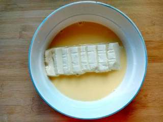 过桥豆腐,把内酯豆腐切厚片，摆放在碗的正中央，然后慢慢倒入蛋液