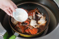 不可错过的酱香梭子蟹 ,放入炸过的梭子蟹，加入适量的白糖后，盖上盖子焖煮10分钟，让蟹入味即可出锅。