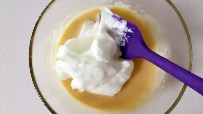 芝麻牛奶华夫饼,取一部分蛋白霜放到步骤3的蛋黄糊中，用橡皮刮刀翻拌、切拌均匀。