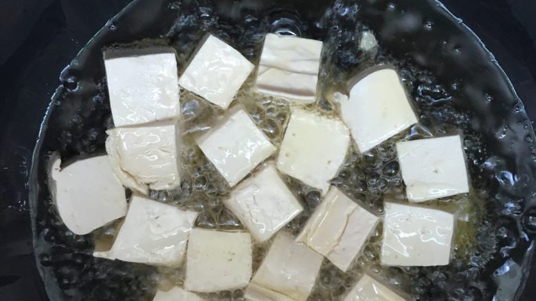 韭苔炒豆腐,油温加热至八成热，将豆腐块逐一放入锅中。