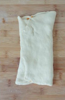 【胡萝卜咸面包】,将面片对折起来包裹住胡萝卜。