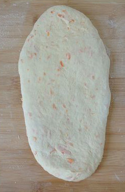 【胡萝卜咸面包】,反复叠压擀开，让胡萝卜丝跟面团融合后再将面团擀成长圆形。