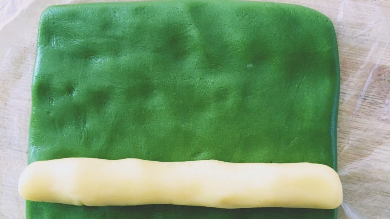 抹茶猕猴桃小饼干,原味面团搓成长约10cm长条，抹茶面团整形成宽10cm的面饼，如图面饼包裹上长条