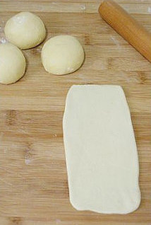 【低粉花生酱面包卷】,取出面团，分割成每50克/个的小面团，将每个面团分别擀薄后卷起两次，然后再擀成长方形。