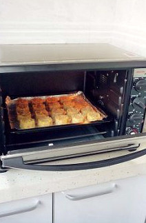 创意西餐：让小朋友喜爱的烤鳕鱼饼 ,鱼饼全部做好后将烤盘放入预热好的烤箱，启动风机，上、下火都是150度，烘烤20分钟即可。