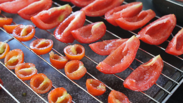 手工的有机美味封存——《日晒番茄 & 橄榄油浸日晒番茄》,用手轻轻将番茄的籽挤掉。把准备好的番茄摆放在烤架上。撒上现磨海盐。