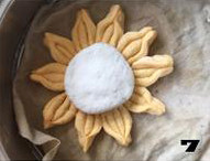 【向日葵面点】,取白色面团揉匀，分成四份揉圆后轻轻按扁放入向日葵花瓣正中。