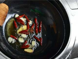 红烧肥肠,锅里放入油，放入姜蒜片、干辣椒、花椒炒出香味。