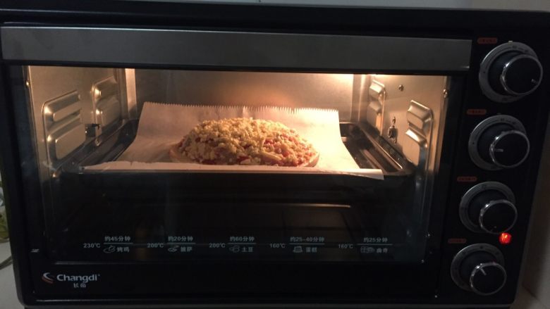 海鲜披萨,这时烤箱调到上下200度预热，将披萨放在油纸上入烤箱，加热20分钟，这期间可以观看到它慢慢变成披萨美丽的样子！