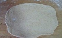 越嚼越香的“核仁葡萄干全麦面包棍”,发好的面团拍气后分割成三小份团成圆形，饧上15分钟，饧好的面团擀成扁长条