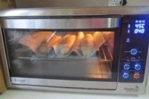 越嚼越香的“核仁葡萄干全麦面包棍”,放入烤箱中，启动烤箱的发酵程序