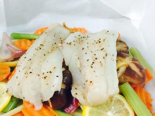 锋味纸包鱼🐟#王氏私房菜#,把腌制好的鳕鱼🐟放在上面、把少许黄油放到鱼🐟上面、把油纸四周全部包住
