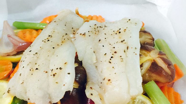 锋味纸包鱼🐟#王氏私房菜#,把腌制好的鳕鱼🐟放在上面、把少许黄油放到鱼🐟上面、把油纸四周全部包住