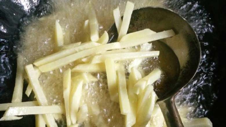 干煸土豆丝,把摸上生粉的土豆条放入油锅中炸。