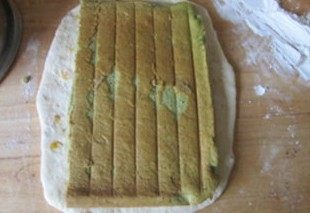 体会不一样的口感----绿茶蛋糕面包,再将面团擀成长条，将刚刚完成的蛋糕一分为二，将一块放在长条的面团上；
