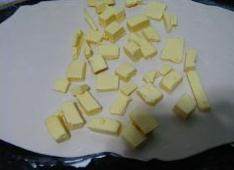 葡式蛋挞,把面团擀成椭圆形薄片，黄油切丁放在面片中间位置。