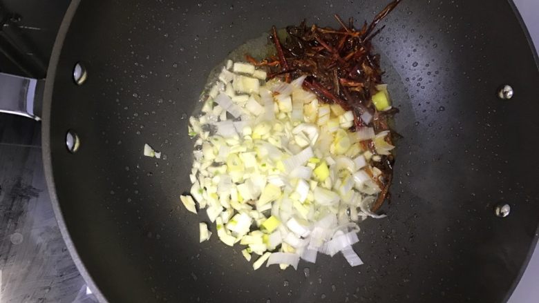 家常小炒肉,将葱、蒜、干辣椒丝放入油锅内