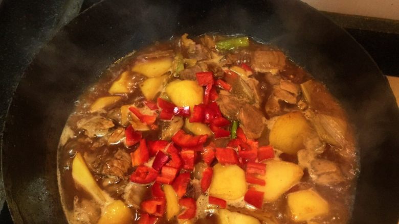 土豆烧牛肉,加入开水（或牛肉汤最好）、红椒粒中火炖煮土豆熟