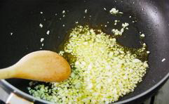 红酒蘑菇牛排,将2大勺的橄榄油倒入锅中加热，放入蒜碎翻炒直到金黄色。